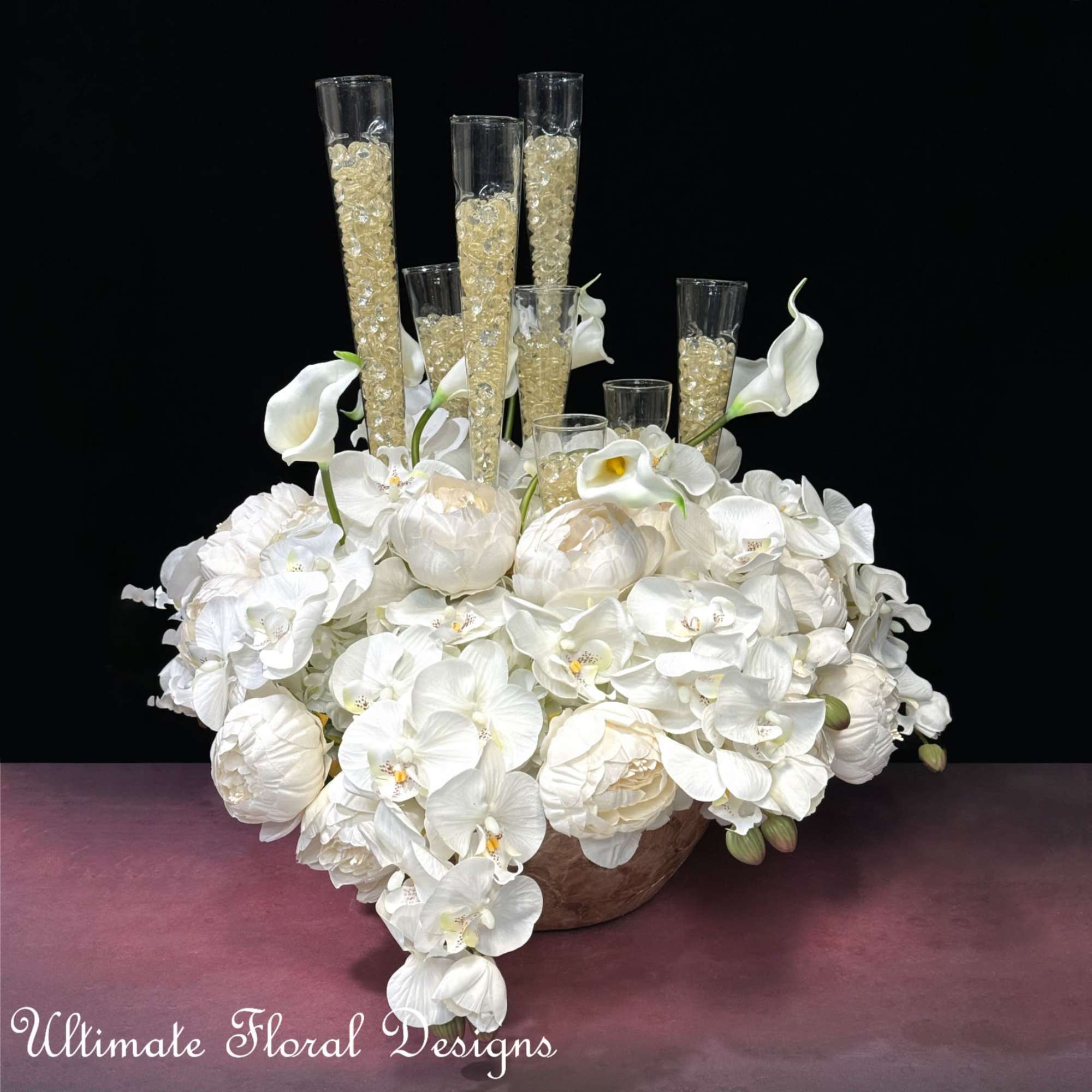 White floral arrangement with orchids, calla lilies, and tall glass cylinders