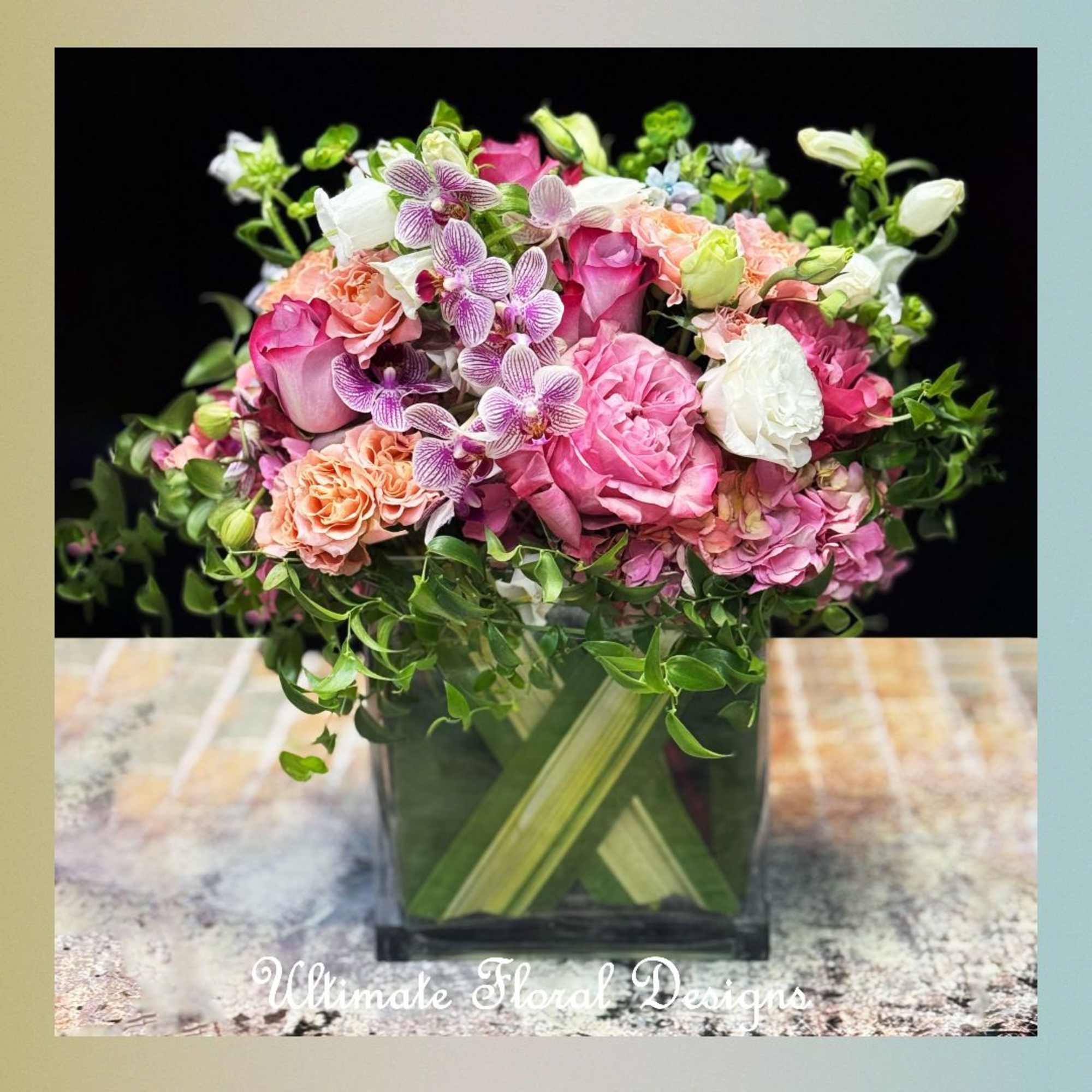 Pink and white floral arrangement in a square glass vase