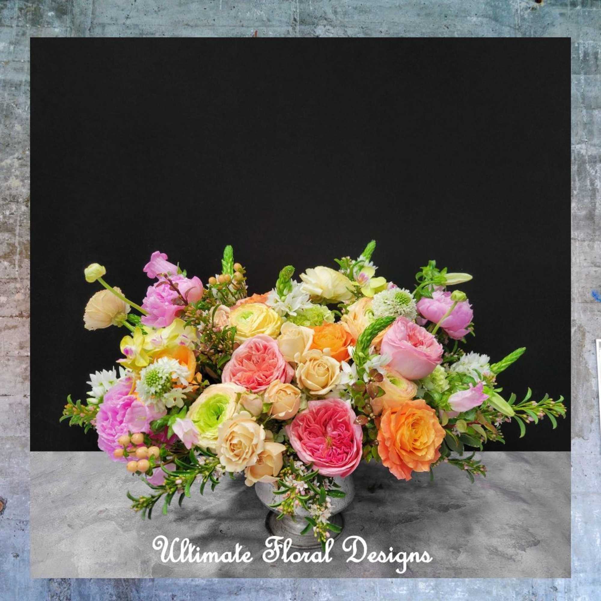 Mixed bouquet of pink, peach, orange, and cream flowers in a low vase