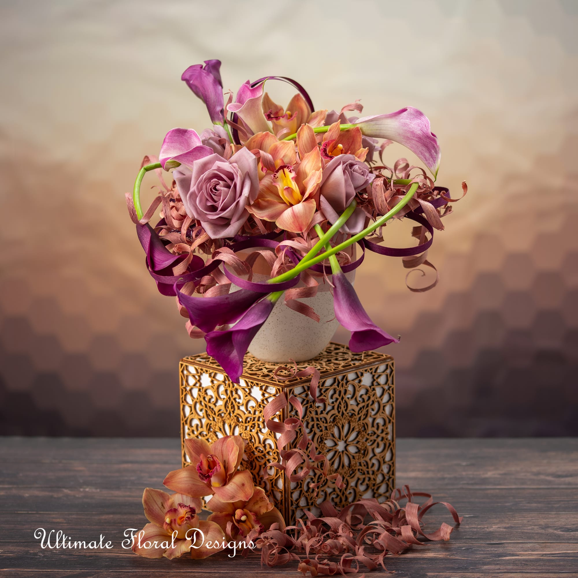 Purple calla lilies and roses arranged in a decorative vase on a gold stand