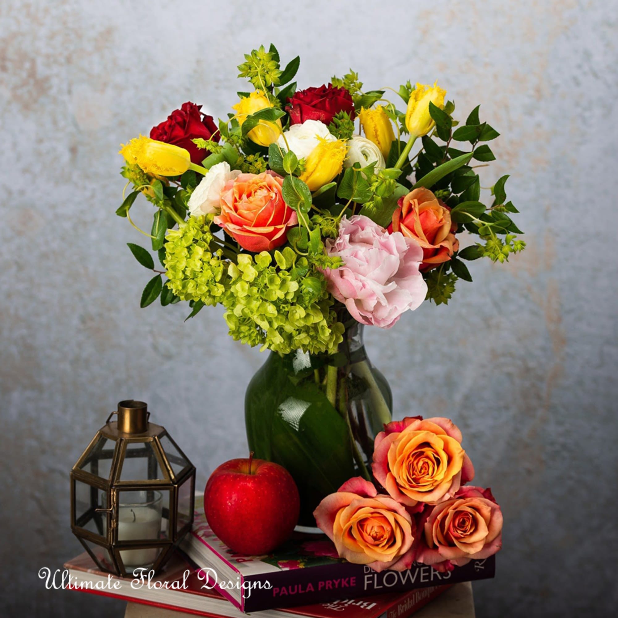 Mixed bouquet of roses and other blooms in a green glass vase