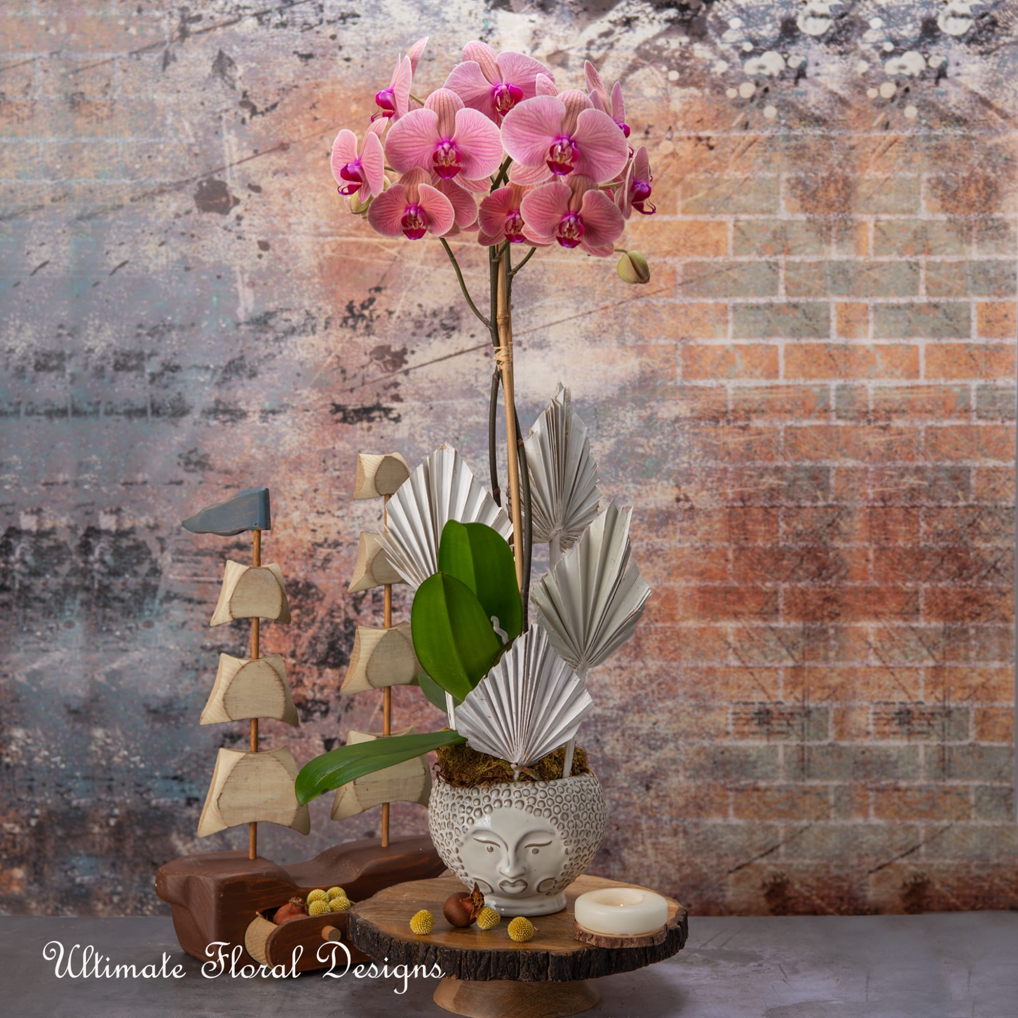 Pink orchid arrangement in a decorative ceramic pot with folded paper accents