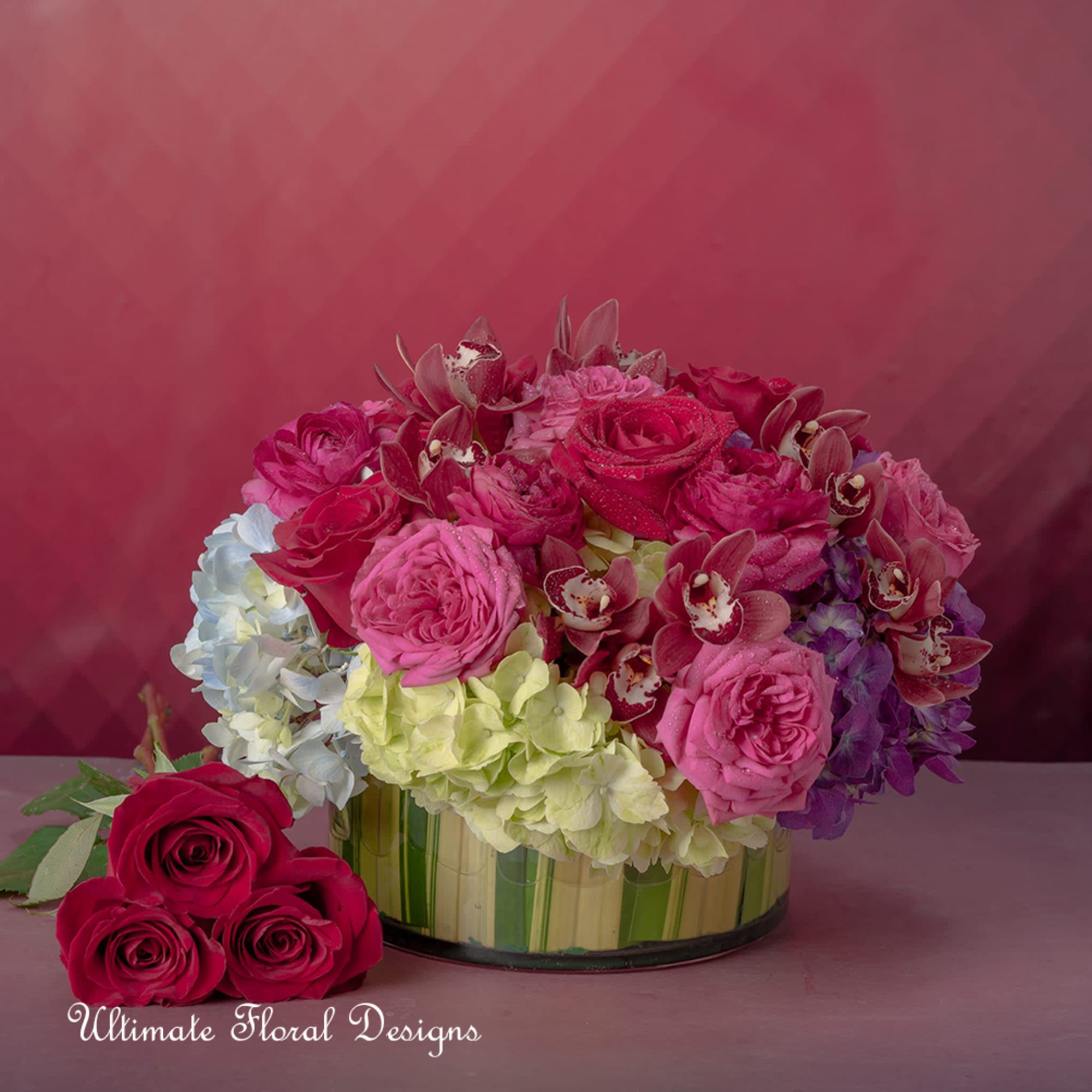 Pink and red roses with hydrangeas in a low glass vase