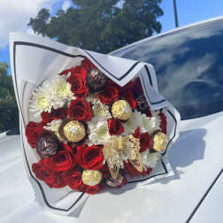 Bouquet of red roses, white daisies, and wrapped chocolates on a car hood