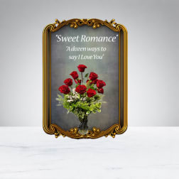 Red roses arranged in a vase beneath a framed romantic sign