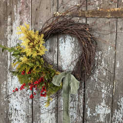 Rustic twig wreath with yellow foliage, red berries, and a green ribbon