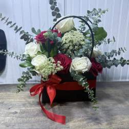 Black basket arrangement of red and white roses with a red ribbon