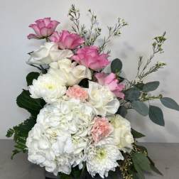 Pink and white floral arrangement with roses, hydrangeas, and chrysanthemums
