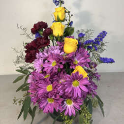 Tall bouquet of purple daisies, yellow roses, and dark red carnations