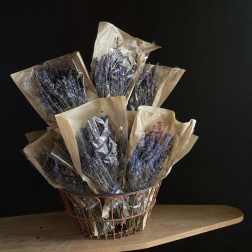 Bundles of dried lavender in paper sleeves inside a wire basket