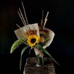 Bouquet with a sunflower and dried grasses in paper wrap