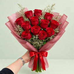 Bouquet of red roses wrapped in pink paper with a red ribbon