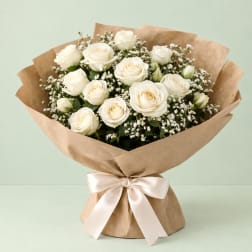 Bouquet of white roses wrapped in brown paper with a satin ribbon
