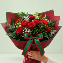 Bouquet of red roses with greenery and a red-green ribbon wrap