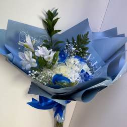 Blue-wrapped bouquet of white and blue flowers with a ribbon