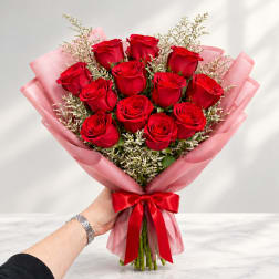 Bouquet of red roses wrapped in pink paper with a red ribbon