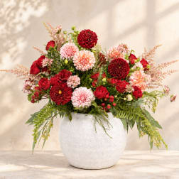 Red and pink mixed flower arrangement in a white vase