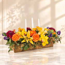Rectangular floral centerpiece with roses, lilies, and three white candles