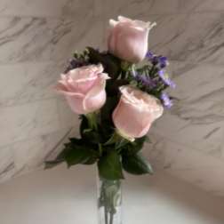 Pink roses with purple filler in a clear glass vase