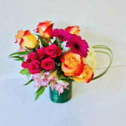 Bouquet of pink and orange roses with magenta daisies in a green vase