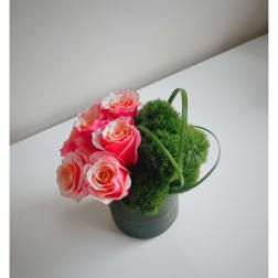 Pink roses arranged with green moss balls in a dark pot