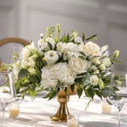 White floral centerpiece in a gold vase on a table