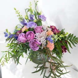 Lavender roses and mixed blooms in a low green vase