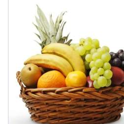 Wicker basket filled with bananas, grapes, oranges, and other fruit