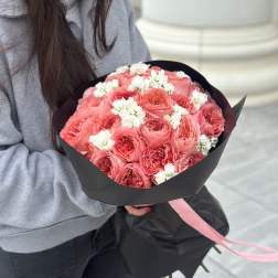 Bouquet of pink roses with small white flowers wrapped in black paper