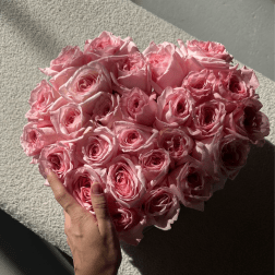 Heart-shaped bouquet of pink roses held in hand