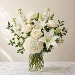 White roses and lilies arranged in a clear glass vase