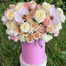Pink and cream rose bouquet in a pink hat box with orchid accents