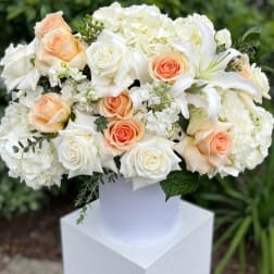 White and peach roses with white lilies in a white vase
