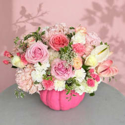 Pink and white floral arrangement in a bright pink pumpkin vase