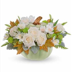 White roses and small white flowers arranged in a pale green pumpkin vase