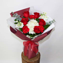 Bouquet of red roses and white flowers wrapped in burgundy paper