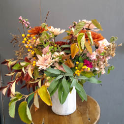 Mixed autumn bouquet in a white ribbed vase with orange and pink blooms