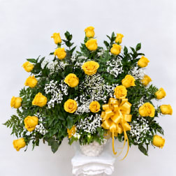 Yellow roses in a white basket with a gold bow