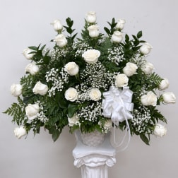 White rose arrangement in a basket with a white ribbon bow