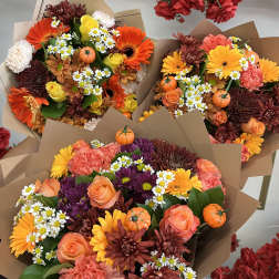 Three mixed bouquets with orange, yellow, and purple flowers wrapped in brown paper