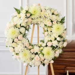 White floral wreath on a wooden easel beside a casket