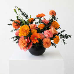 Orange and pink mixed bouquet in a black vase