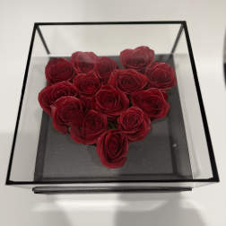 Heart-shaped arrangement of red roses in a clear square box