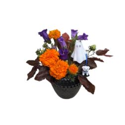 Orange and purple floral arrangement in a dark vase with Halloween figurines