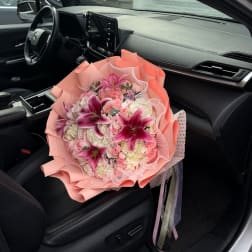 Pink and white bouquet with lilies and roses on a car seat