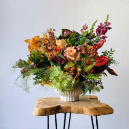 Mixed floral arrangement in a white vase with orange, pink, and red blooms