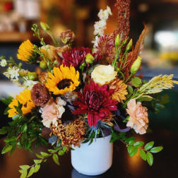 Mixed bouquet of sunflowers, chrysanthemums, and carnations in a white vase