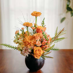 Orange floral arrangement in a black vase on a table