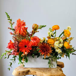 Bright mixed flower arrangement in a white rectangular vase