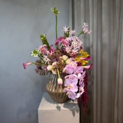 Mixed pink and purple flowers arranged in a ribbed glass vase